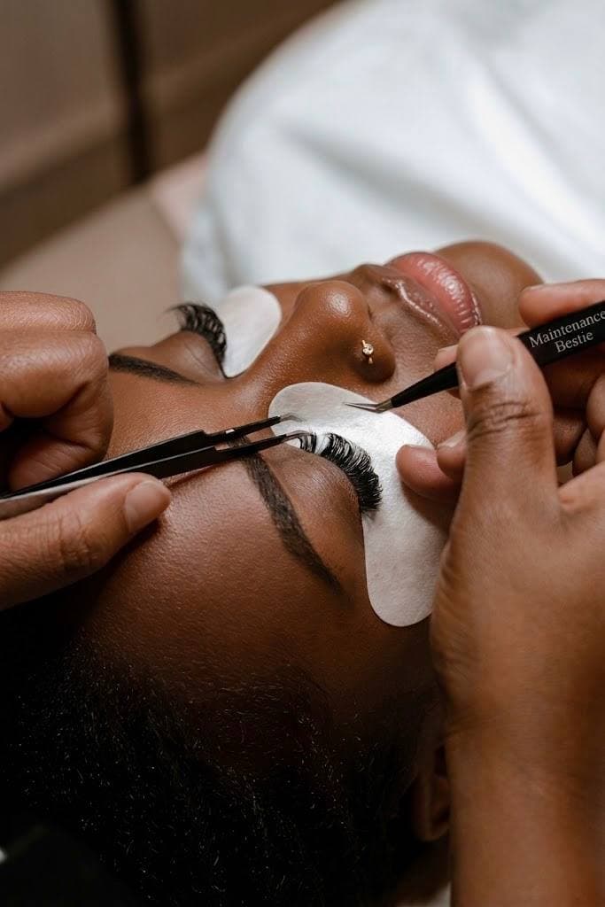 A lash technician applying volume extensions with tweezers